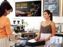 Lady ordering at coffee shop with digital signage in background