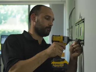 Man drilling to install a screen on wall