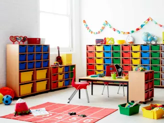 A nursery with brightly coloured wooden table, chairs and storage lockers with toys on the floor.