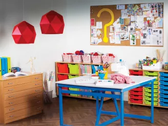 Brightly coloured table, bookcases and wooden drawers in a primary school classroom