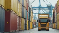 Truck navigating narrow passageway amidst stacks of shipping containers, glimpse into modern logistics