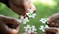 Hands holding puzzle pieces with sustainable images demonstrating how sustainable Manufacturing can be achieved through Microsoft Dynamics 365 Business Central