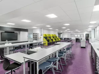 School classroom with rows of classroom chairs and desks with AV screen mounted on the wall