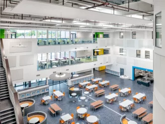 Birds eye view of open plan school area with bench tables and seating, curved cushioned seating and banks of desks and chairs.