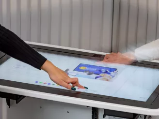 Interactive touchscreen table being used by two people in collaboration