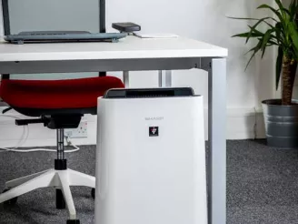 sharp plasmacluster air purifier sat at foot of desk in office