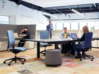 People sat on ergonomic task chairs at wooden desks working