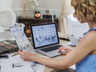 Female furniture designer working at desk with paperwork and computer