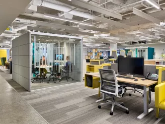 Open plan modern office with working pods and yellow, black and grey office furniture