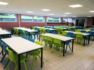 Blue and green plastic chairs with white desks in a secondary school classroom