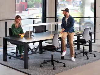 Man and woman sat at modern meeting room table with task chairs