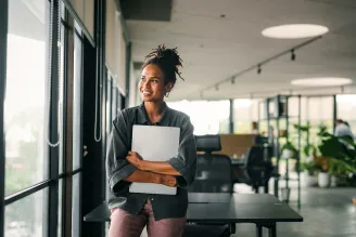 Woman holding laptop in office space, reaping the benefits of Sharp's On-Premise Backup Solutions