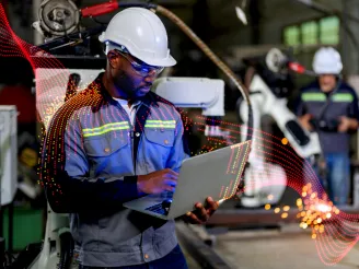 Man working in manufacturing plant with laptop in hand