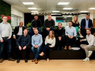 A group of IT professionals on a tiered seating smiling at the camera