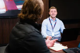A Sharp employee sat at a table with a laptop talking to a woman