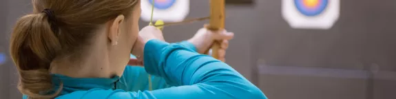 Woman pointing at a target with a bow and arrow 
