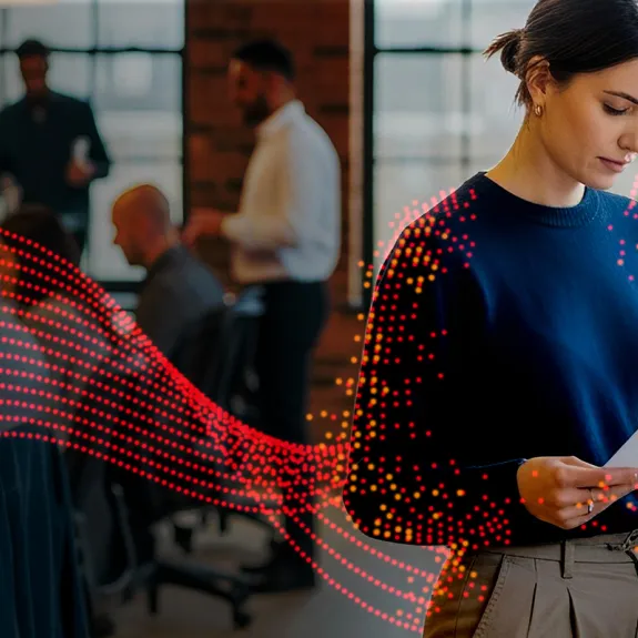 A woman standing beside a Sharp printer reading a document