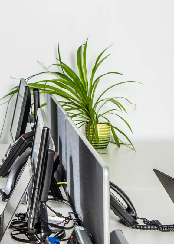 Two men in the partner support team sat at desks working with laptops laughing together