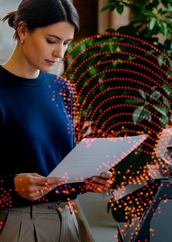 Woman standing in front of a Sharp MFP looking at a document