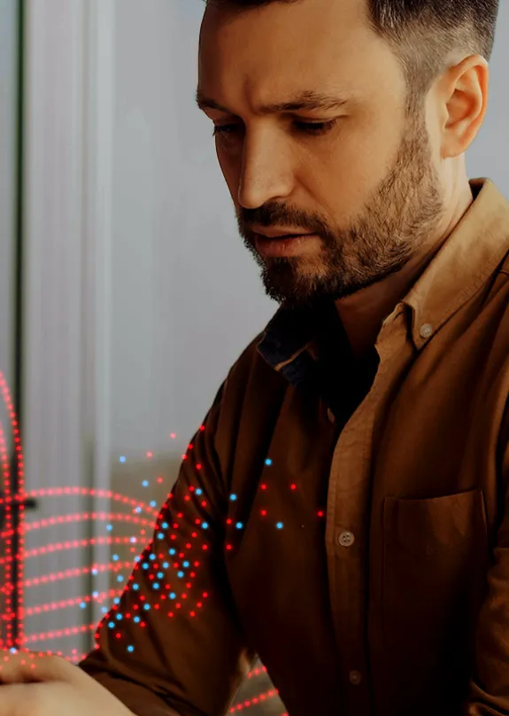 Man looking at both a phone and laptop 