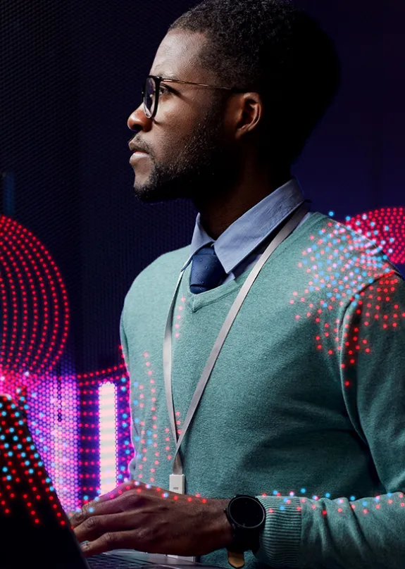 Man typing on laptop and looking at computer server