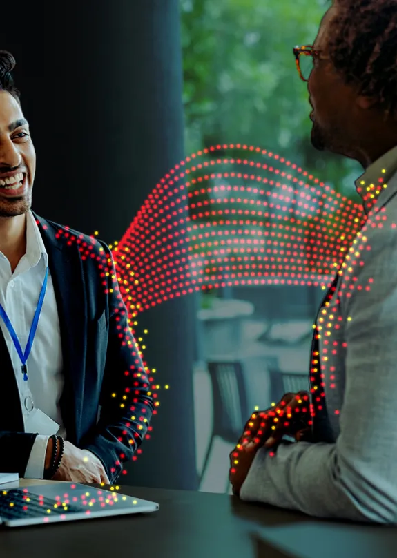 Two men sat chatting by a laptop 