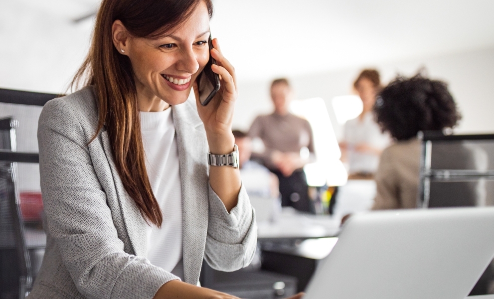 Woman in the workplace on a laptop and mobile speaking with clients with secure endpoint security