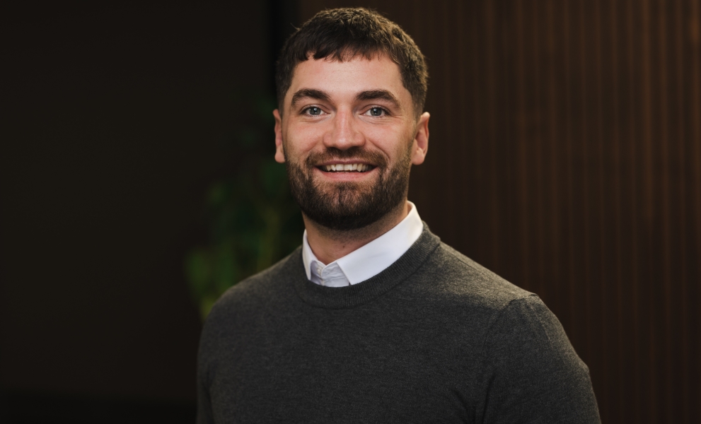 Man wearing jumper and shirt smiling as he has his picture taken for a photoshoot