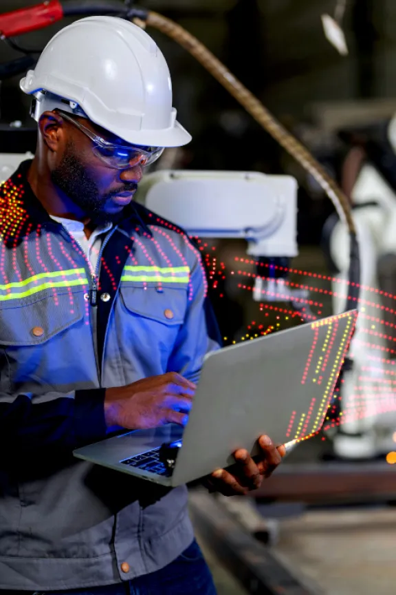 Man working in manufacturing plant with laptop in hand
